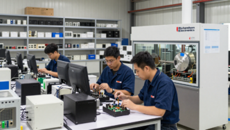 Technicians inspecting electronic components and semiconductor equipment in an industrial workspace.