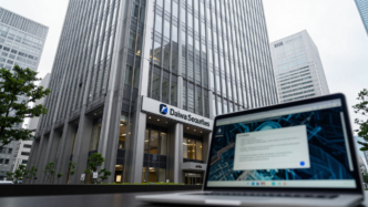 Daiwa Securities office building in Tokyo with a laptop showing a cybersecurity alert