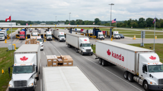 Freight trucks approach customs booths at a Canada–United States border crossing.