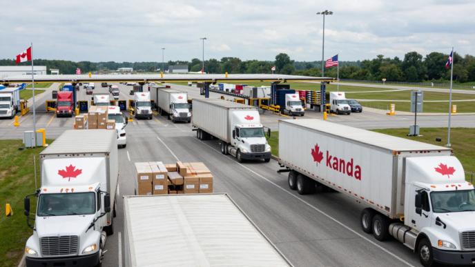 Freight trucks approach customs booths at a Canada–United States border crossing.