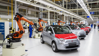 Fiat 500 hybrid cars moving along an automotive assembly line in an Italian factory.