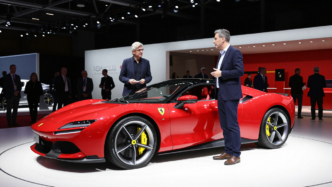 John Elkann and Jony Ive beside Ferrari’s Luce electric car at a Turin conference.