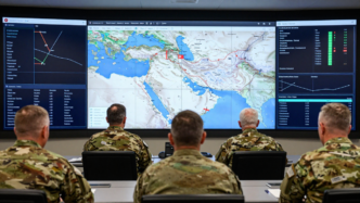 Military planners study a Middle East map in an operations room.