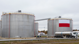 Oil storage tanks at a Polish reserve facility beneath a Polish flag.