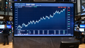 Traders watch a rising S&P 500 chart on a market display.