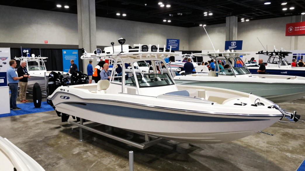 Attendees examine a recreational powerboat and supplier displays at a marine-industry trade show.