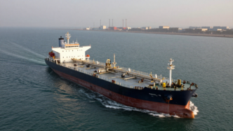 Crude oil tanker transiting the Strait of Hormuz near Gulf port infrastructure.