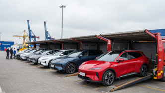 Chinese-made electric cars at a British port beside freight cranes