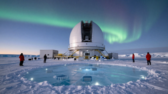 The IceCube research facility at the South Pole beneath a starry Antarctic sky.