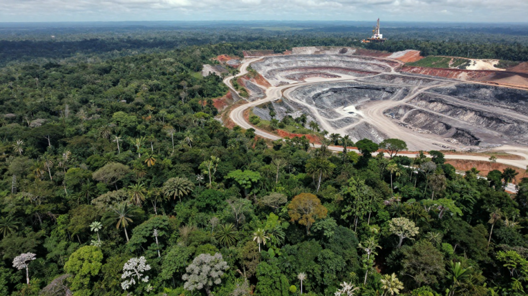 Aerial view of intact tropical forest beside a large open-pit mine