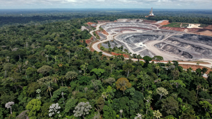 Aerial view of intact tropical forest beside a large open-pit mine