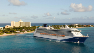 Royal Caribbean cruise ship sailing near a Caribbean beachfront resort.