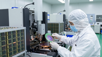 Cleanroom engineer inspecting a silicon wafer in a semiconductor fabrication facility.