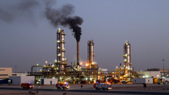Flames and smoke rise near an Aramco facility south of Riyadh as emergency vehicles respond.