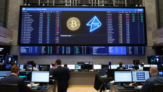 Exchange trading screens show Bitcoin, Ether and commodity market indicators.